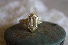 an antique diamond ring sitting on top of a green stone slab with white fur in the background