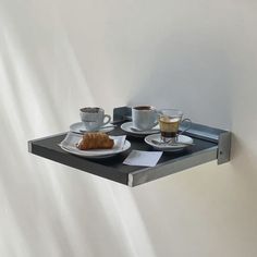 two plates with coffee and croissants sit on a metal shelf next to each other