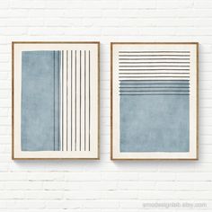 two framed art pieces on a white brick wall, one with blue and grey lines