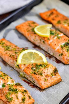 salmon with herbs and lemon slices on a baking sheet