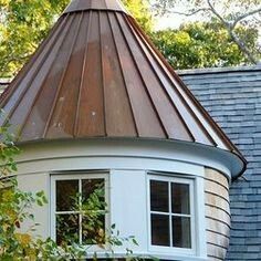 a round window on the side of a house with a metal roof and shingles