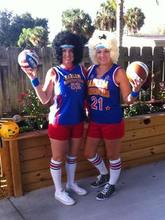 two women dressed in cheerleader outfits holding footballs