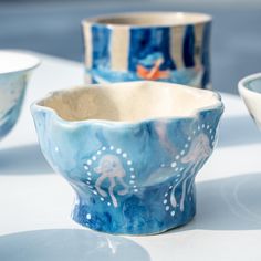 three bowls sitting on top of a table next to each other with designs on them