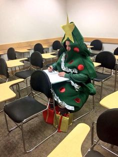 a person in a christmas tree costume writing on a piece of paper