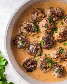 meatballs and gravy in a bowl with parsley on the side