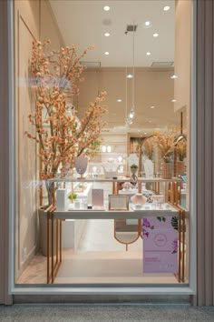 a store front window with an assortment of vases and trees in the display case