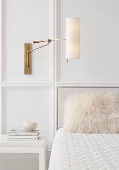 a bed with a white blanket and a wall light