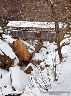 a man walking across a snow covered bridge