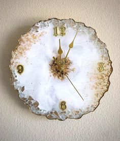 a clock that is on the wall with numbers and numerals in gold paint