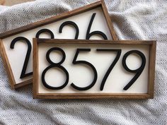 two wooden signs with numbers on them sitting on top of a white cloth covered surface