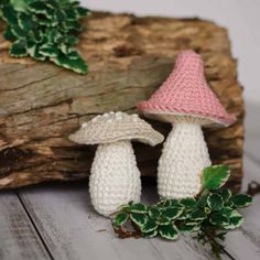 two crocheted mushrooms sitting next to each other on a piece of driftwood