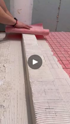 a person is sanding the floor with a pink cloth