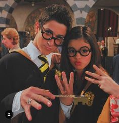 two people dressed in harry potter costumes posing for the camera with their hands up and fingers out