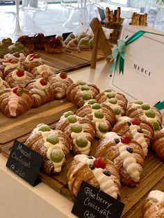 many pastries are displayed on wooden trays