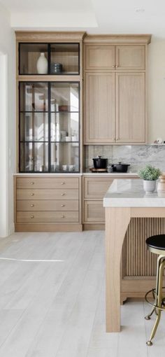 a kitchen with wooden cabinets and marble counter tops, along with two stools in front of the island