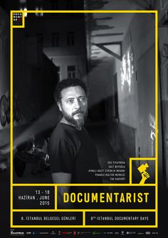 a man with a beard standing in front of a black and white poster that says documentarist