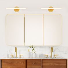 a bathroom with two sinks, mirrors and gold faucets on the countertop