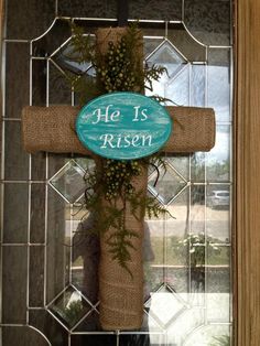 a cross hanging from the side of a door with a sign that says he is risen