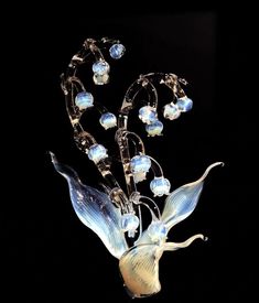 a glass vase with flowers and beads in it's center on a black background