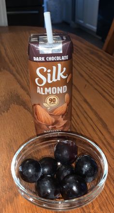 a glass bowl filled with black olives next to a carton of silk almond milk