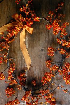 a wreath made out of branches with red berries on it and a ribbon tied to the front