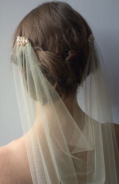 the back of a woman's head wearing a white veil with pearls on it