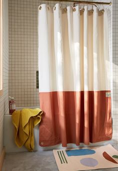 a bath room with a toilet and a shower curtain next to a rug on the floor