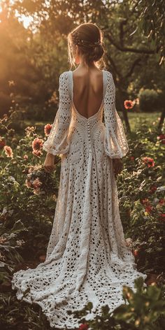 a woman in a white crochet dress is standing in the middle of flowers