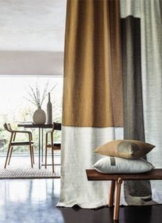 a living room filled with furniture next to a window covered in white and brown curtains