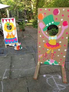 two cardboard easels with paintings on them sitting in the middle of a patio area