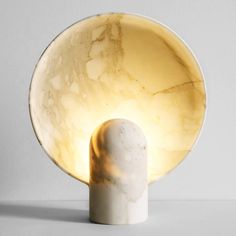 a white marble table lamp with a yellow light on it