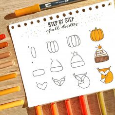 some markers and pencils sitting on top of a piece of paper with an image of pumpkins