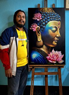 a man standing in front of a painting on easel next to a pink flower