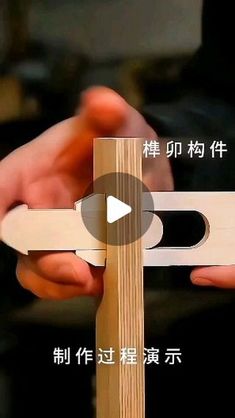 two hands holding a piece of wood with the words in english and chinese on it