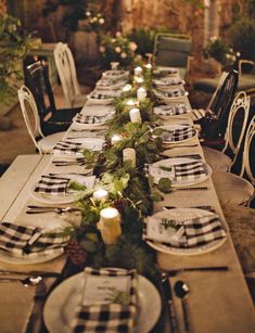 the table is set with black and white checkered placemats, greenery, candles, and plates