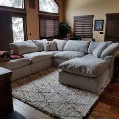 a large sectional couch sitting on top of a rug in a living room next to windows