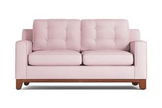 a pink couch sitting on top of a white floor next to a wooden leg chair