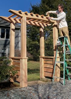 a man standing on a ladder next to a wooden structure