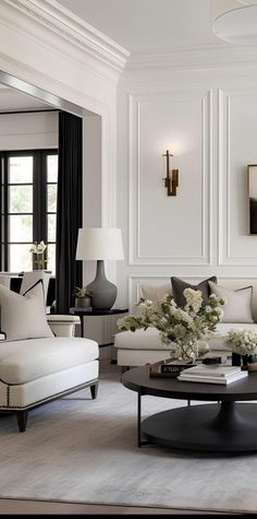 a living room filled with white furniture and lots of black and white decor on the walls