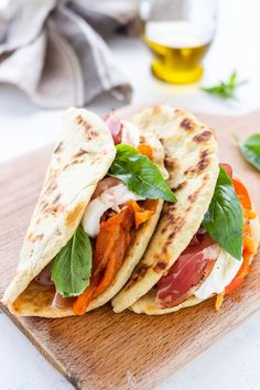 three pita breads with meat and vegetables on a cutting board