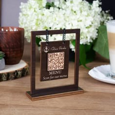 a wooden frame with a qr code on it sitting next to a cup of coffee