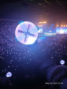 a person holding up a round object in front of an audience at a music concert