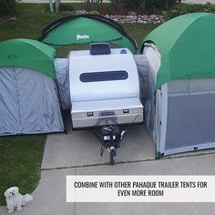 there are two tents and a trailer on the sidewalk with a dog standing next to it