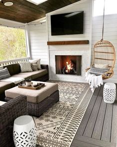 a living room with wicker furniture and a fire place in the fireplace, along with a large screen tv