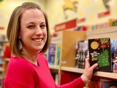 a woman is holding up a book in a library