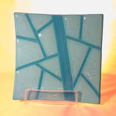 a blue glass plate sitting on top of a yellow tableclothed surface with lines drawn across it