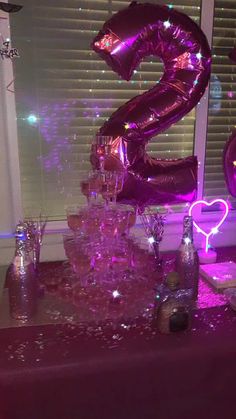 a table topped with lots of balloons and confetti on top of it next to a window