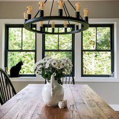 a dining room table with vases and flowers on it in front of a large window