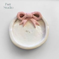 a white bowl with pink bows on the top and bottom that says pott studio