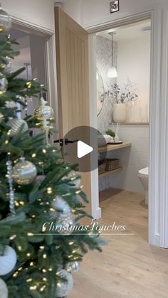 a christmas tree is in the middle of a room with white walls and wood floors